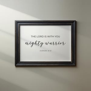May include: A black framed print with the text "The Lord is with you mighty warrior" and the scripture reference "Judges 6:12".