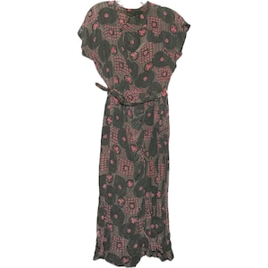 May include: A floor-length dress featuring a dark gray and pink geometric pattern with circular and square motifs. The garment has short sleeves, a round neckline, and a matching fabric tie belt at the waist, creating a wrap-style silhouette.