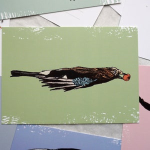 May include: A green postcard with a black and white illustration of a bird carrying a red berry in its beak. The bird is flying with its wings spread out. The postcard has a distressed, vintage look.