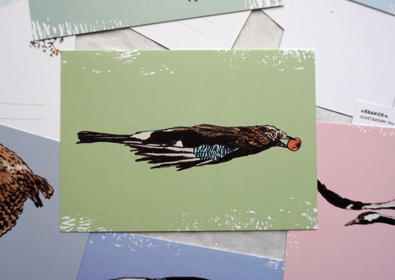 May include: A green postcard with a black and white illustration of a bird carrying a red berry in its beak. The bird is flying with its wings spread out. The postcard has a distressed, vintage look.