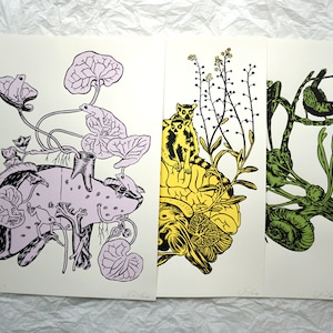 May include: Three prints featuring a pink, yellow and green colour scheme. The pink print depicts a frog on a plant with a pink and white spotted creature. The yellow print features a lemur on a yellow brain-shaped object with a green plant. The green print shows a bird on a green branch with a snail.