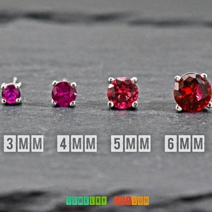 May include: Four silver stud earrings with red gemstones. The earrings are shown in sizes 3mm, 4mm, 5mm, and 6mm.