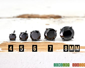 May include: Five black round stud earrings in different sizes, ranging from 4mm to 8mm. The earrings are displayed on a wooden surface with the size of each earring labeled below it.