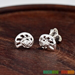 May include: A pair of silver earrings shaped like nautilus shells with a small clear rhinestone in the center of each shell.
