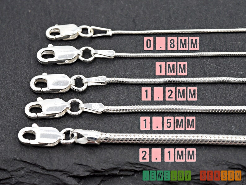 K&ouml;nnte beinhalten: F&uuml;nf silberne Schlangenketten in verschiedenen St&auml;rken, beschriftet mit ihren Ma&szlig;en in Millimetern: 0,8 mm, 1 mm, 1,2 mm, 1,5 mm und 2,1 mm.