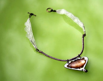 May include: A delicate necklace with a white lace trim and a copper wire chain. The pendant is a heart-shaped piece of copper with a white enamel inlay.