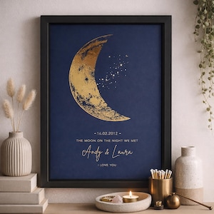 May include: A framed art print with a gold crescent moon and stars on a navy blue background. Text reads "16.02.2012 - THE MOON ON THE NIGHT WE MET" and "Andy & Laura I LOVE YOU". The print is in a black frame.