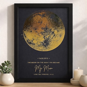 May include: A framed art print with a gold foil moon design on a dark background. The text reads "16.02.2012, The Moon on the Night You Became, My Mum, Love You Forever, Julia." The print is in a black frame.