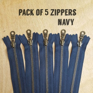 May include: Pack of 5 navy blue zippers with antique brass pulls.