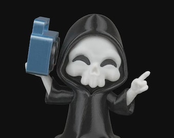 May include: A figurine of the Grim Reaper in a black hooded robe, with a white skull face and hands. The Reaper is holding a blue object in one hand and pointing with the other. The figurine has a cartoonish design.