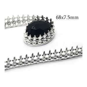 May include: A silver-toned metal crown setting featuring a decorative fleur-de-lis edge and a faceted black oval stone, accompanied by a matching silver-toned metal strip with a fleur-de-lis pattern, labeled with the dimensions 68x7.5mm.