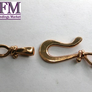 May include: Gold-tone metal clasp with a knotted loop on one end and a hook on the other end.  The clasp is approximately 1.5 inches long.