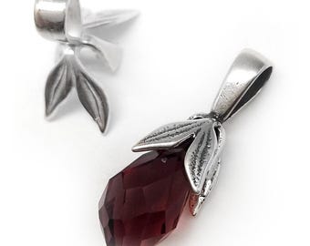 Puede incluir: Dos colgantes de metal plateado con un cristal facetado en forma de lágrima de color rojo intenso. Cada colgante tiene una anilla en la parte superior y un engaste decorativo en forma de hoja que rodea la base del cristal metálico.