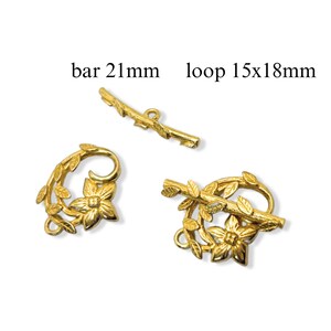 May include: Gold-tone metal clasp with a floral design. The clasp has a bar that is 21 mm long and a loop that is 15 mm by 18 mm.