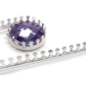 Peut inclure: Un accessoire de coiffure en métal argenté doté d'un sertissage en forme de couronne. Une pierre précieuse ronde et facettée de couleur violette est fixée dans le support circulaire. L'accessoire présente une longue tige droite et dentelée.