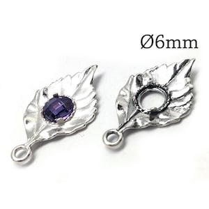 Puede incluir: Dos dijes de metal plateado con forma de hoja y una anilla en la base. Uno tiene una piedra ovalada morada facetada engastada, mientras que el otro es un engaste vacío. El texto Ø6mm es visible, indicando un diámetro de 6mm.
