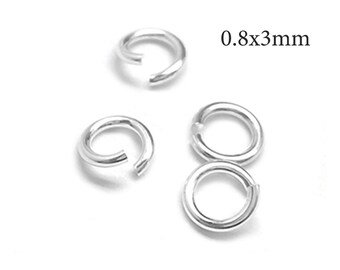 Puede incluir: Tres anillas de salto de metal plateado con forma circular y una pequeña abertura. Las anillas tienen un acabado liso y reflectante. El texto 0.8x3mm está impreso en negro junto a las anillas, indicando su tamaño específico.
