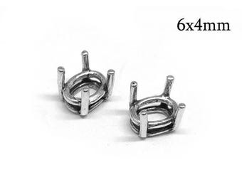 May include: Two silver-colored metal oval ring settings with four prongs each, designed for 6x4mm stones. These jewelry components feature a polished finish and a classic basket-style structure for securing gemstones in place for jewelry making.