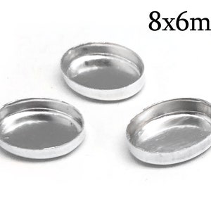 Może przedstawiać: Trzy srebrne, owalne, metalowe przedmioty przypominające tace, każdy o wymiarach 8 mm na 6 mm.