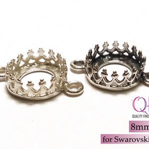 K&ouml;nnte beinhalten: Zwei kronenf&ouml;rmige Schmuckfassungen aus silberfarbenem Metall mit kreisf&ouml;rmigen &Ouml;sen an jeder Seite. Die Fassungen sind f&uuml;r 8mm Steine, speziell f&uuml;r Swarovski SS39, ausgelegt. Der Text QFM Quality Findings Market ist sichtbar.