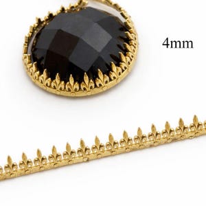 May include: A black, faceted gemstone in a gold-coloured metal setting, with a fleur-de-lis trim. The image also shows a 4mm measurement and a length of gold-coloured fleur-de-lis trim, ideal for jewellery making or embellishments.