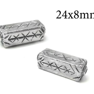 Pode incluir: Duas contas de metal prateado com um padrão geométrico. Cada conta mede 24 mm x 8 mm.
