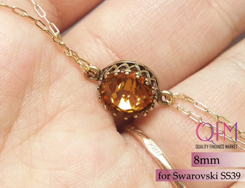K&ouml;nnte beinhalten: Eine goldfarbene Metallfassung mit einem runden, facettierten bernsteinfarbenen Kristall. Die Fassung hat einen dekorativen gewellten Rand und ist an einer feinen Goldkette befestigt. Der Text auf dem Bild lautet 8mm for Swarovski SS39.