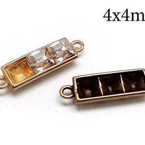 Może przedstawiać: Dwa złote metalowe elementy łączące z kwadratowym kryształem o wymiarach 4x4 mm w środku jednego elementu. Drugi element ma trzy kwadratowe wgłębienia.