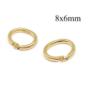 May include: Two gold-coloured metal jump rings with a hinged opening mechanism. Each ring features a small protruding pin and a corresponding hole for closure. The text 8x6mm is printed in black above the rings, indicating their size.
