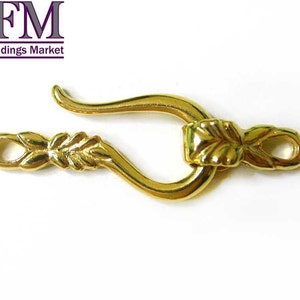 May include: Gold-toned metal clasp with a leaf design. The clasp has a hook on one end and a loop on the other.