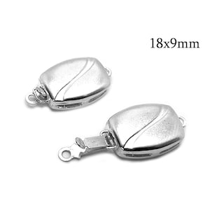 May include: Two silver-toned metal clasps with a wave design. Each clasp measures 18mm by 9mm.