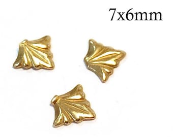 May include: Three small gold-colored metal embellishments shaped like stylized leaves or fans. Each piece features a textured, radiating pattern and measures 7x6mm as indicated by the text printed in the upper right corner of the image.
