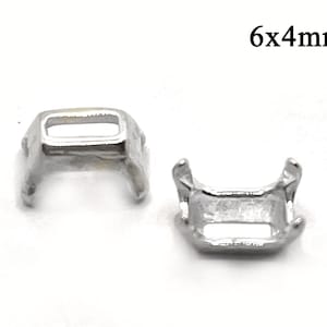 May include: Two small, silver-colored metal components, each with a rectangular opening and curved supports. The text "6x4mm" is visible in the upper right corner, indicating the size of the components.