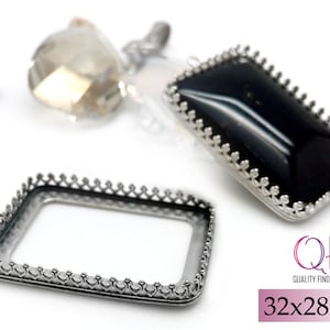 May include: Silver-toned metal frame with a decorative border, measuring 32x28mm. The frame is designed to hold a rectangular piece of glass or other material.