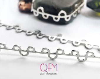 Puede incluir: Cadena de plata con un patrón repetitivo de círculos unidos. La cadena es de metal y tiene un acabado pulido.