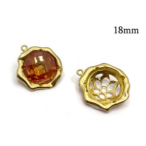May include: Two gold-tone metal pendant charms, each measuring 18mm. One charm features a clear orange faceted gemstone, while the other has a decorative openwork design.