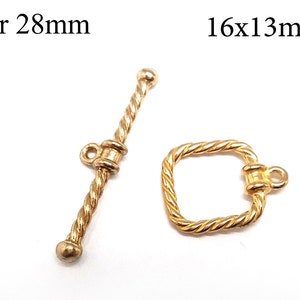 Könnte beinhalten: Goldfarbene Metallverschlüsse zum Schmuckmachen. Ein Verschluss ist eine 28 mm lange Stange mit einem gedrehten Seildesign. Der andere Verschluss ist ein 16 mm x 13 mm großes Quadrat mit einem gedrehten Seildesign.