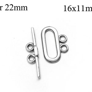 Könnte beinhalten: Silberfarbener Metallverschluss mit einem 22 mm langen Steg und einer 16 x 1 mm großen ovalen Schlaufe. Der Verschluss hat zwei kleine Ringe am Steg zum Anbringen von Schmuck.
