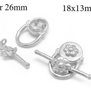 Könnte beinhalten: Silberfarbene Schmuckverschlüsse mit Blumen- und Ovalmotiven. Der Steg ist 26 mm lang, die Verschlüsse sind 18x13 mm. Diese Verschlüsse eignen sich für Halsketten, Armbänder und andere Schmuckprojekte. Die Verschlüsse sind aus glänzendem Metall.