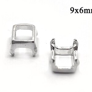 May include: Two small, silver-colored metal findings. The findings are rectangular with a U-shaped opening. The text "9x6mm" is in black font above the findings. These findings are likely used in jewelry making or crafts.