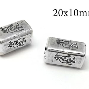 Pode incluir: Duas contas retangulares de prata com um desenho nativo americano gravado na superfície. As contas medem 20 mm x 10 mm.