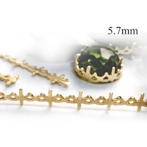 Pode incluir: Close-up de componentes de joias douradas. Inclui uma corrente em forma de cruz, uma pedra preciosa verde em uma moldura dourada e outras peças decorativas. O texto "5,7 mm" é visível.