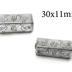 May include: Two silver rectangular beads with a design of birds and reeds. The beads are 30x11 mm.