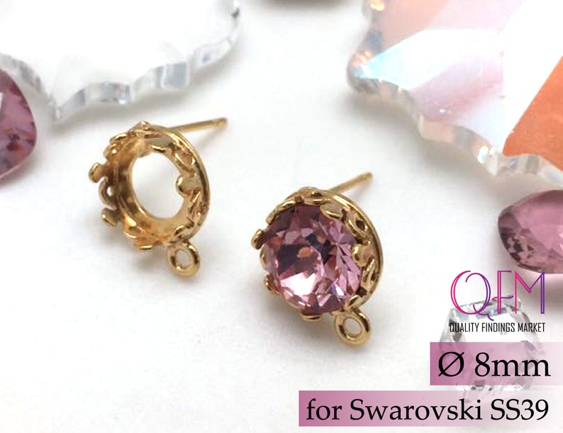 May include: Gold-tone earring settings with a 8 mm round opening, designed to fit Swarovski SS39 crystals. The settings have a delicate crown design and a loop for attaching a dangle charm.