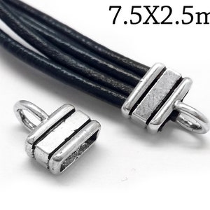 Könnte beinhalten: Zwei silberfarbene Metall-Kordelenden mit rechteckiger Form und einer kleinen Schlaufe. Die Enden sind 7,5 mm x 2,5 mm groß.