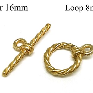 Könnte beinhalten: Zwei goldfarbene Metallverschlüsse zum Schmuckbasteln. Der Verschluss links ist ein Stabverschluss mit einer Länge von 16 mm. Der Verschluss rechts ist ein Schlaufverschluss mit einem Durchmesser von 8 mm. Beide Verschlüsse haben ein seilartiges Design.