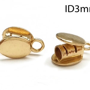 May include: Gold-toned metal cord end with a 3 mm inner diameter. The end has a round, flat top and a small loop on the side.