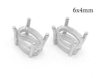 May include: Two silver-colored oval gemstone settings, each featuring four prongs for securing a stone. The metal components are designed for jewelry making and are labeled with the text 6x4mm, indicating the specific dimensions of the setting.