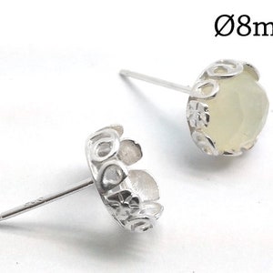 May include: Two silver earring settings with a delicate floral design. Each setting is 8mm in diameter and features a round, clear stone.