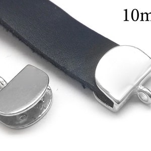 May include: Two silver metal clasps for leather straps, each with a loop for attaching to a strap. The clasps are 10mm in size.